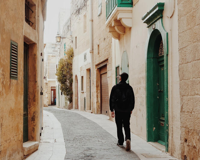 A man walking up a historic street looking around at the scenery